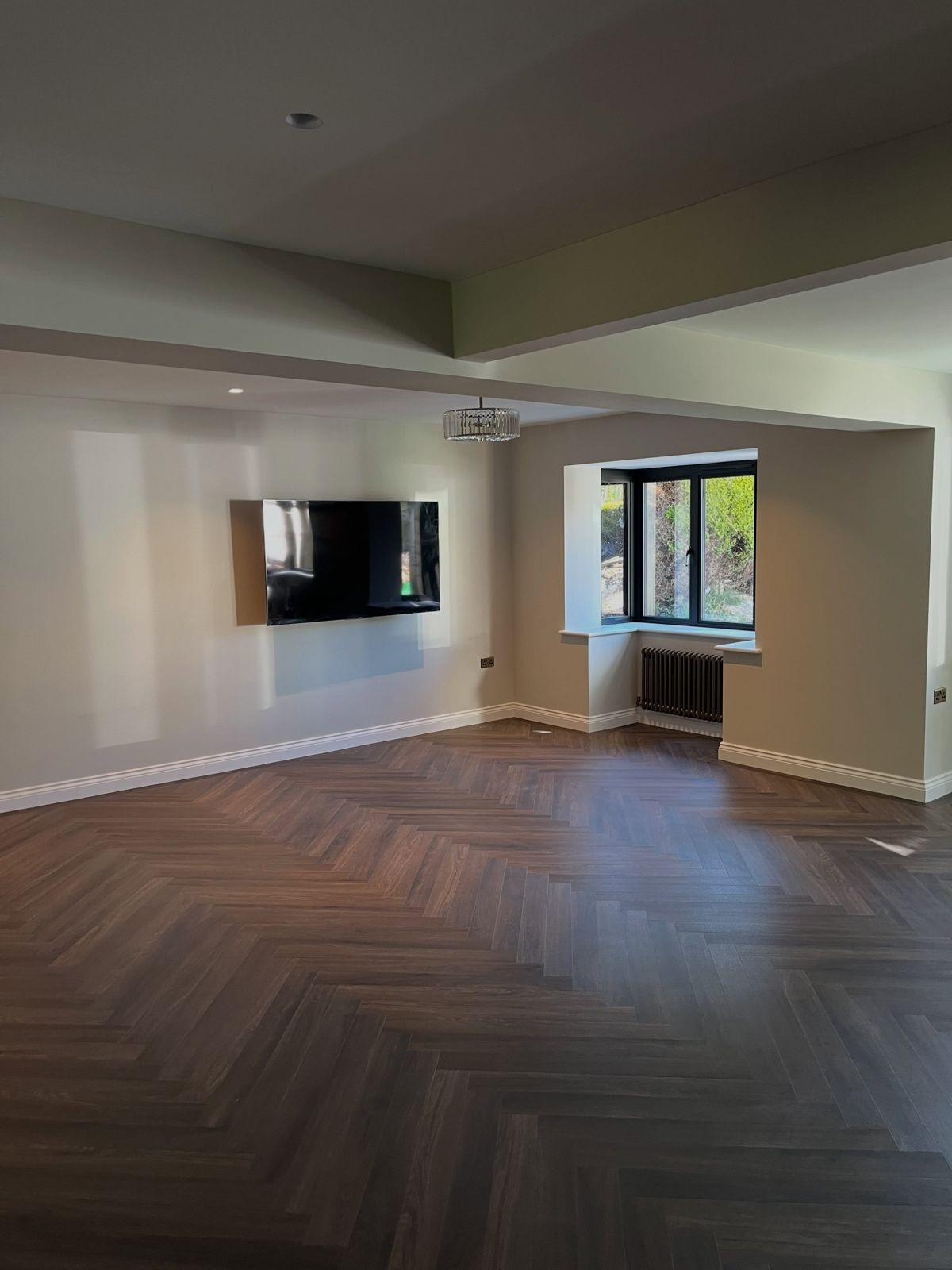 Open-plan room with new herringbone LVT flooring and wall-mounted TV